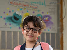 A girl in glasses poses for a photo in an IRC classroom in Iraq.